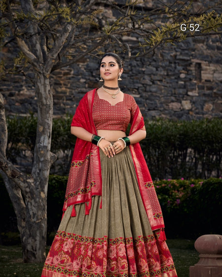 Woman wearing a traditional red and green outfit with a stone wall and trees in the background