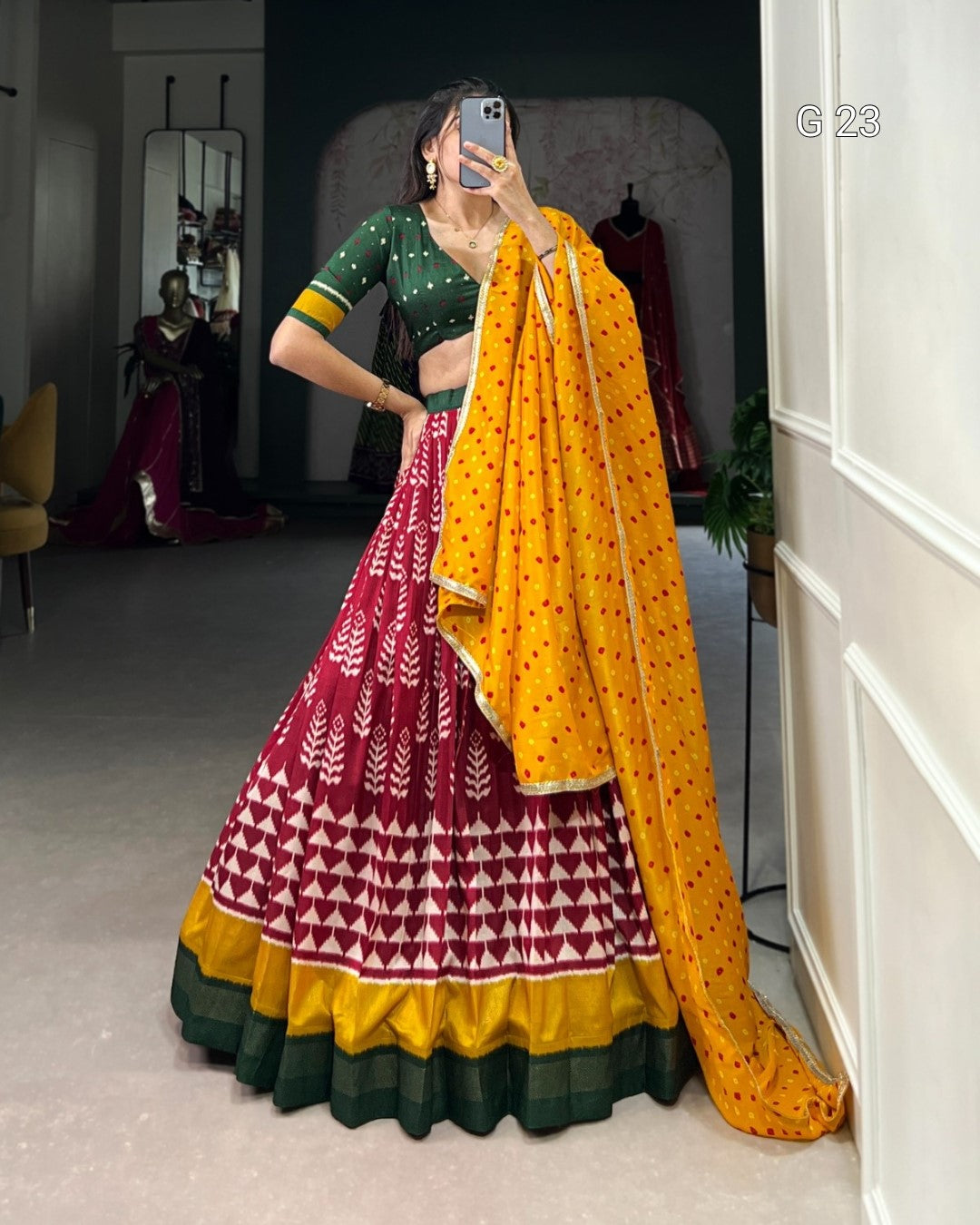 Woman in a colorful traditional outfit with a yellow saree in a room.