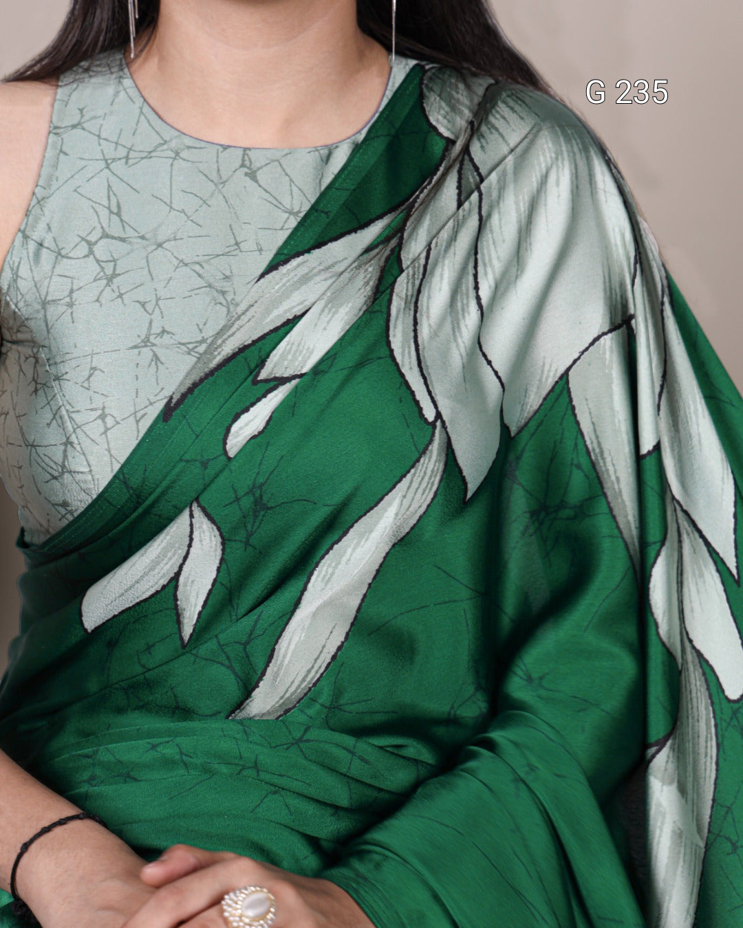 Green saree with leaf patterns worn by a person, on a neutral background.