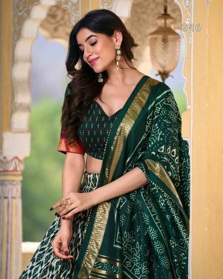 Woman wearing a green saree with gold details in an ornate setting