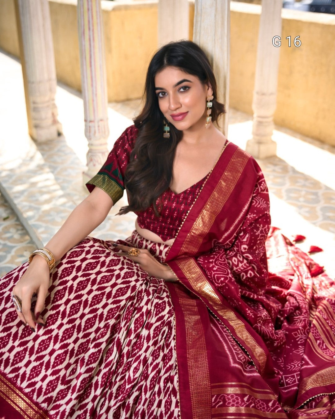 Woman wearing a traditional maroon saree with white patterns indoors.