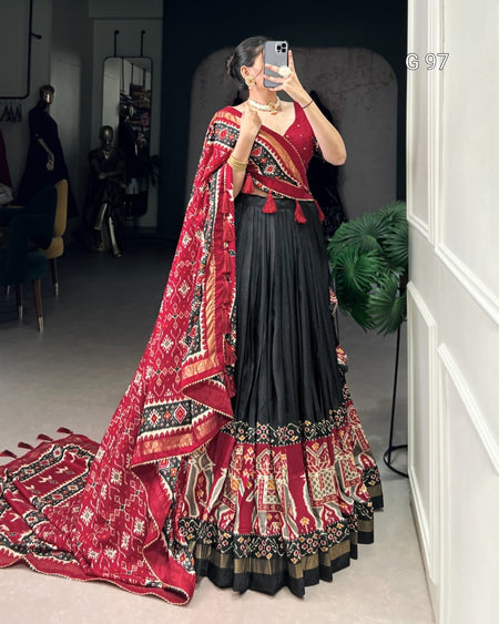 Woman in a traditional outfit with a red and black patterned shawl in a room.
