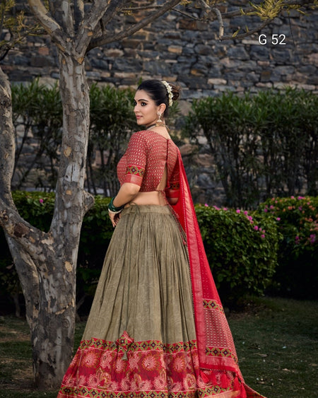 Woman in a traditional outfit with red and green colors standing outdoors.