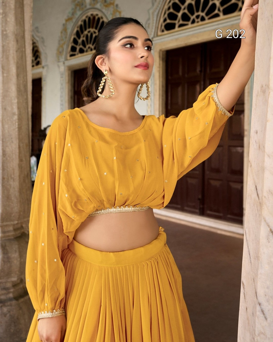 Woman in a yellow traditional outfit standing in an ornate doorway.